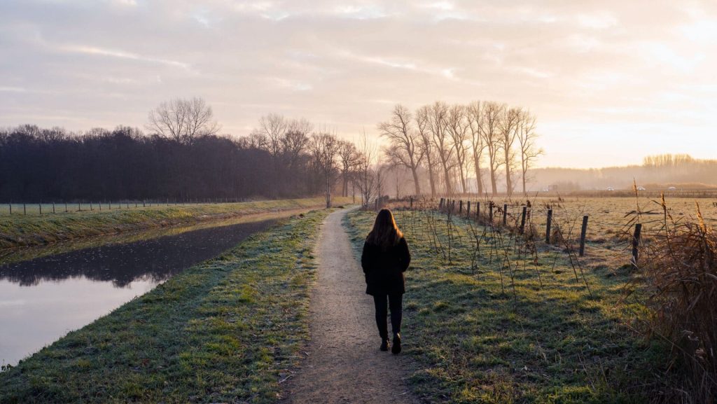 photo of a hiker on a countryside path next to a river to illustrate self-guided walking vacations in Dorset