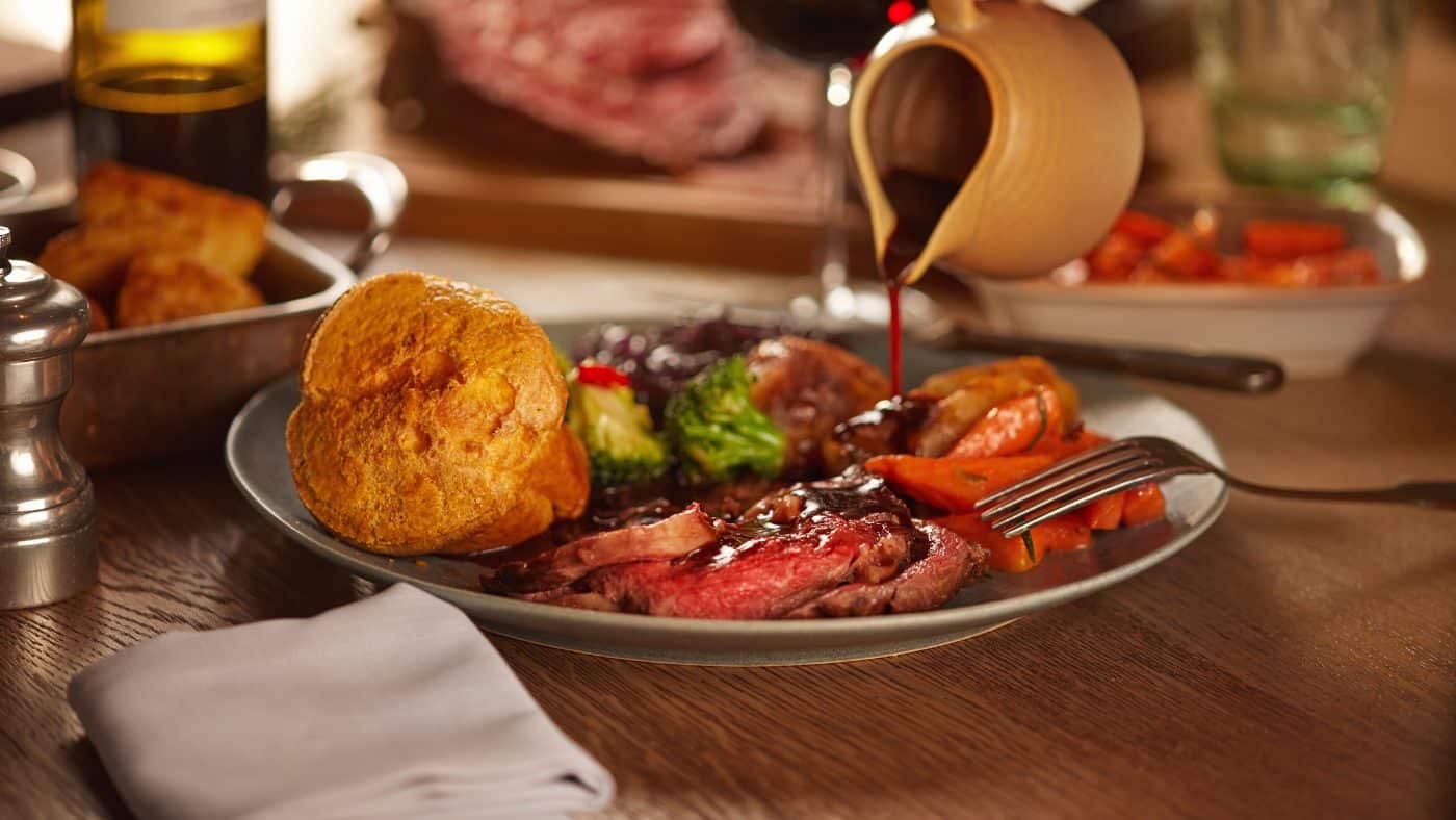 photo of rich gravy being poured over a traditional British roast dinner