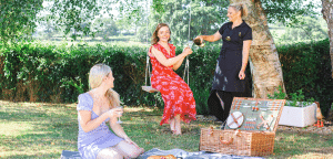 photo of Laura with a guest on swing and picnic scene