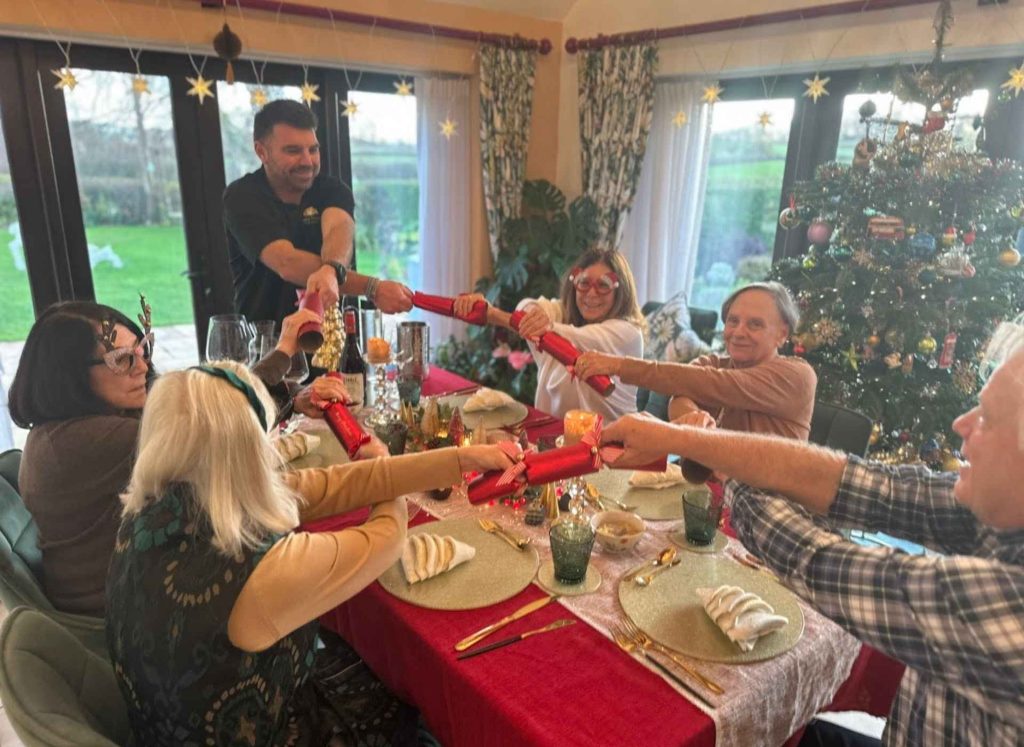 photo of Nathan pulling Christmas crackers with guests at Well Cottage